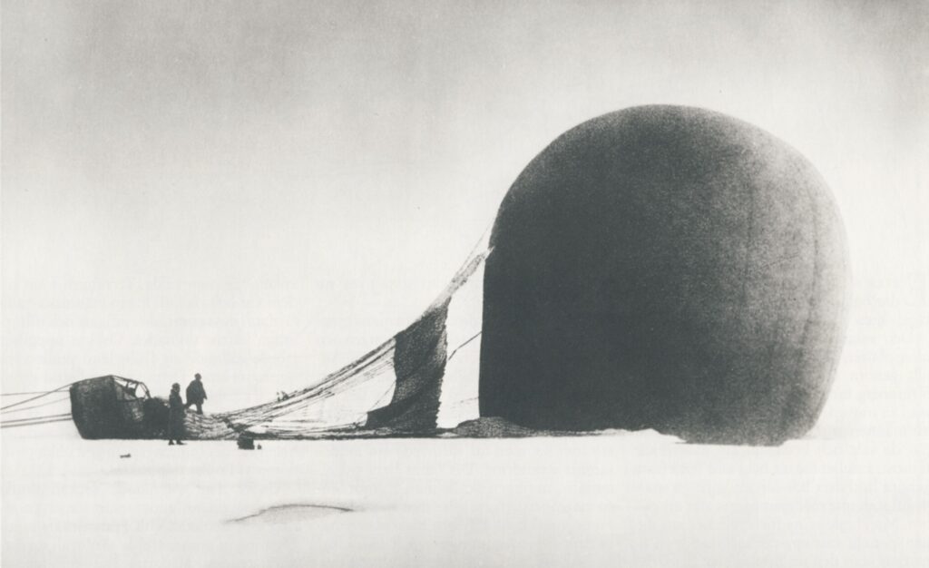 Eine große, kugelförmige Struktur dominiert die schneebedeckte Landschaft und ist durch gespannte Seile mit kleineren Gebäuden verbunden, bei denen mehrere Personen stehen.